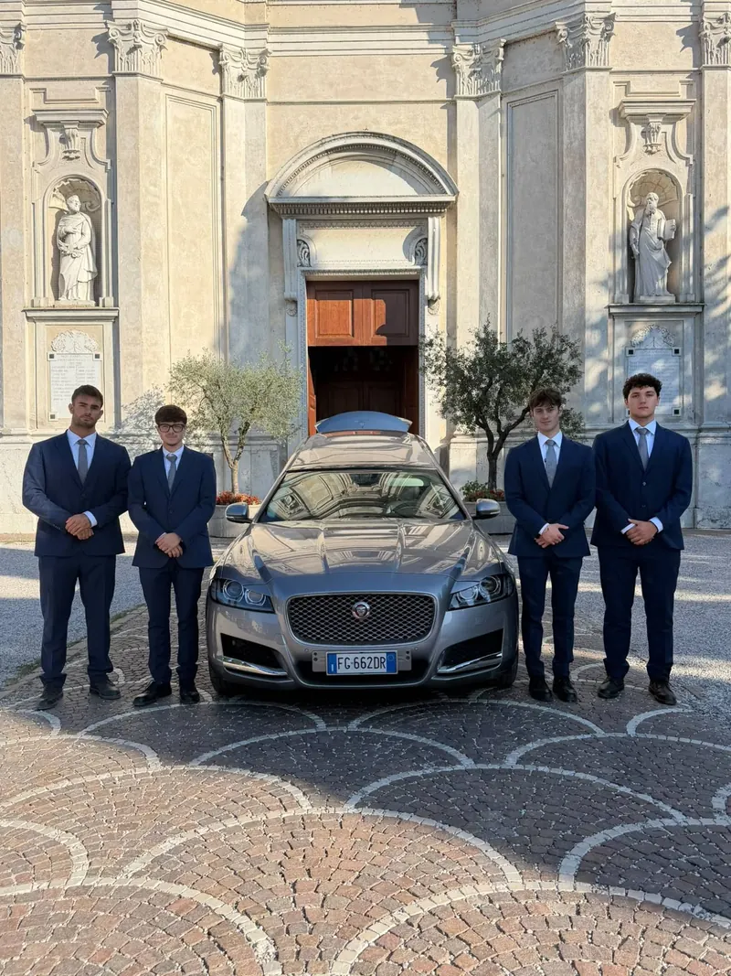 I nostri accompagnatori in abito scuro accanto all’auto funebre, davanti alla chiesa