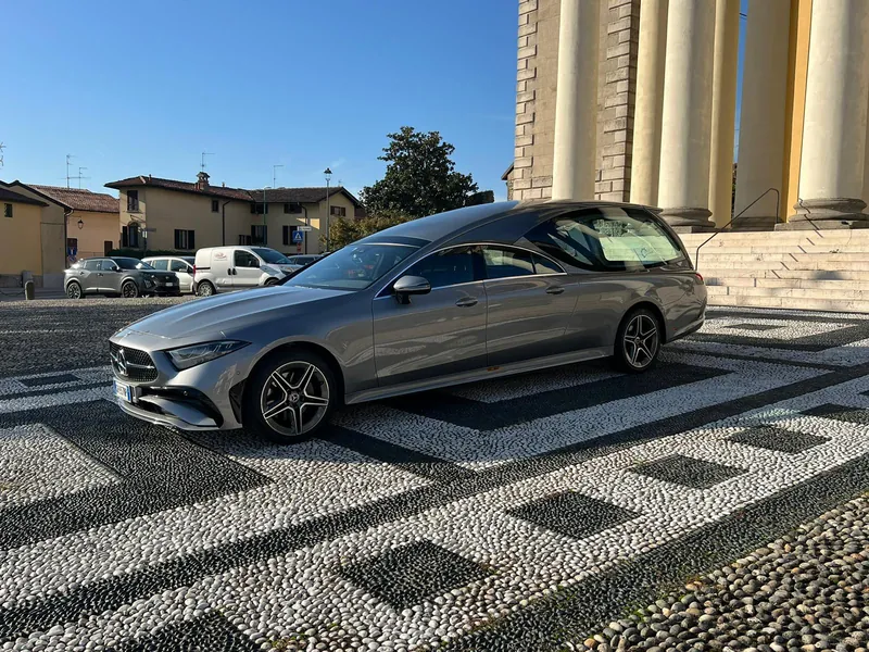 Auto funebre Mercedes grigia di Onoranze Funebri Menegardo davanti a una chiesa